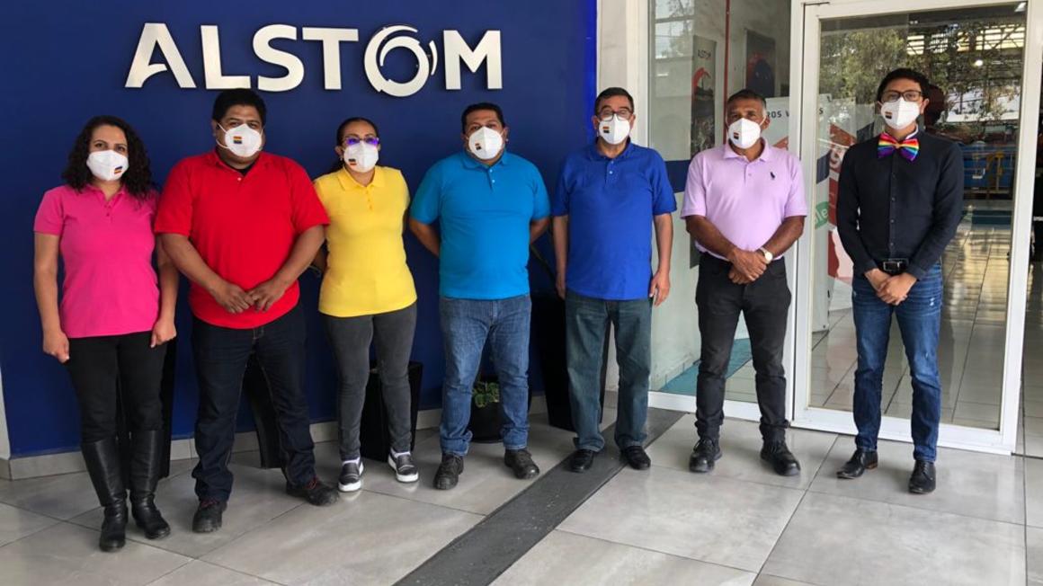 Copyright: ALSTOM People in rainbow shirts standing in front of Alstom sign