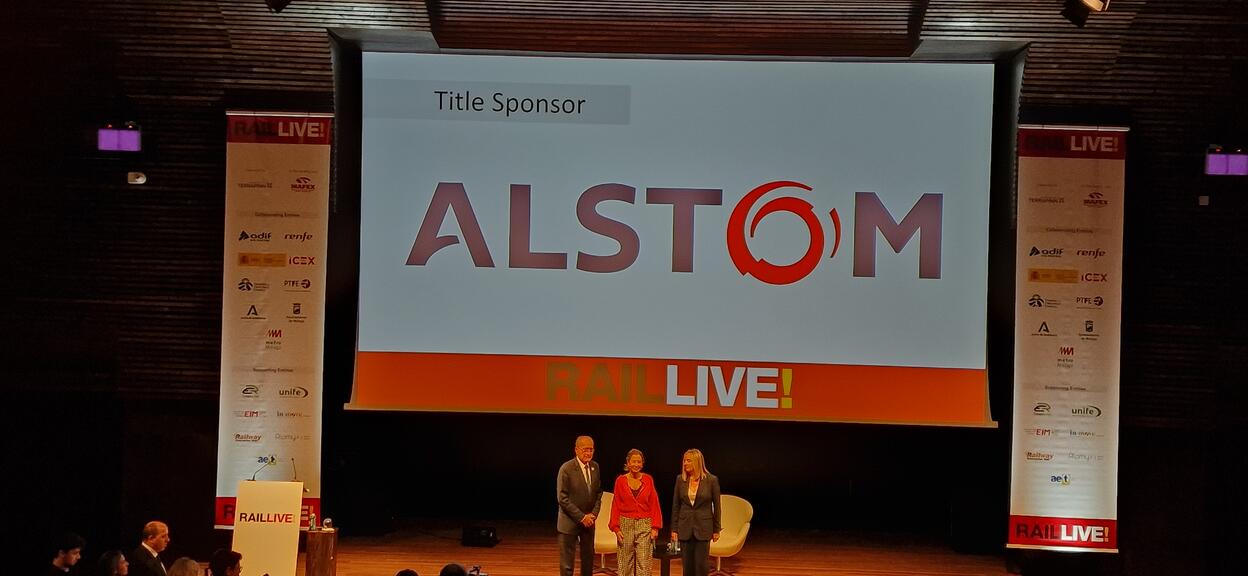People on stage at Rail Live! 2022 with ALSTOM logo behind