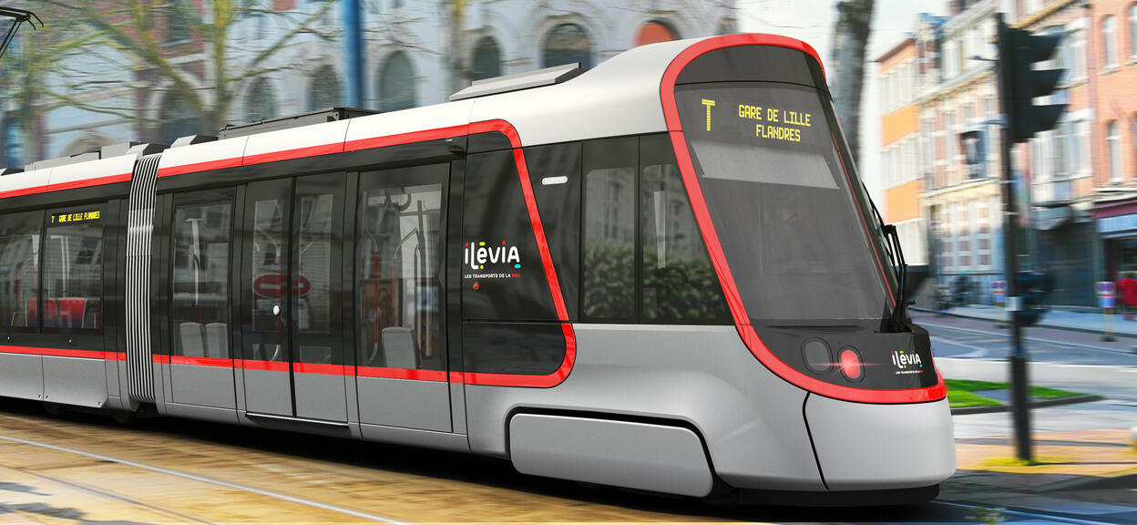 A Citadis tram bearing the logos of Ilevia is shown travelling from left to right along a tree-lined avenue. The train’s display screen shows its destination (Gare de Lille Flandres)