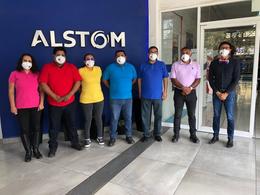 People in rainbow shirts standing in front of Alstom sign