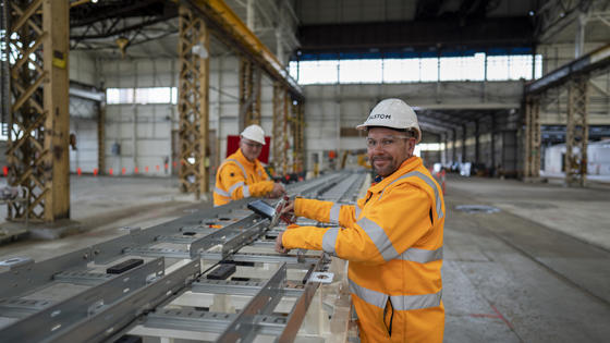 2 Alstom employees in orange jackets working in a site