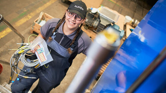 Alstom, Kassel site, mechatronics technician Ann-Katrin Heinel climbing the stairs of a  Traxx locomotive body with cables in her hand