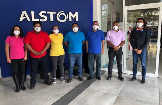People in rainbow shirts standing in front of Alstom sign