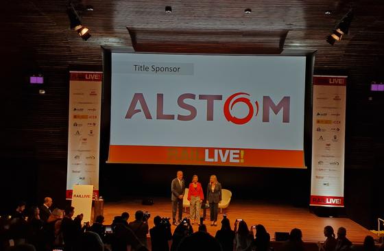 People on stage at Rail Live! 2022 with ALSTOM logo behind