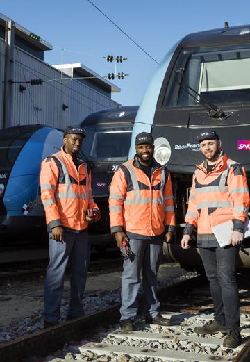 3 employees standing in front of blue train