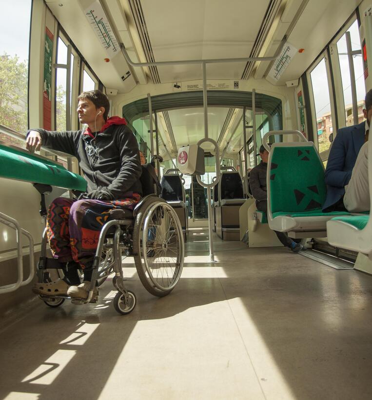 Passenger in wheelchair looking out window in metro car